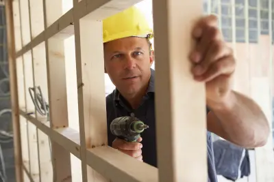 homme dans le bâtiment construisant une charpente avec perceuse